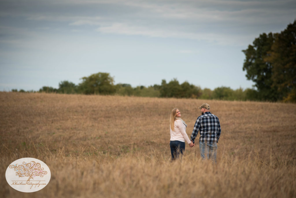 Bride to be looks at camera in a field during engagement session