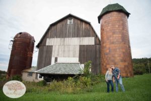 Couple kissing in front of barn and silos in Weedsport NY