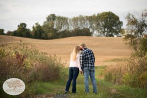 Engagement photo of couple kissing in a field of grass