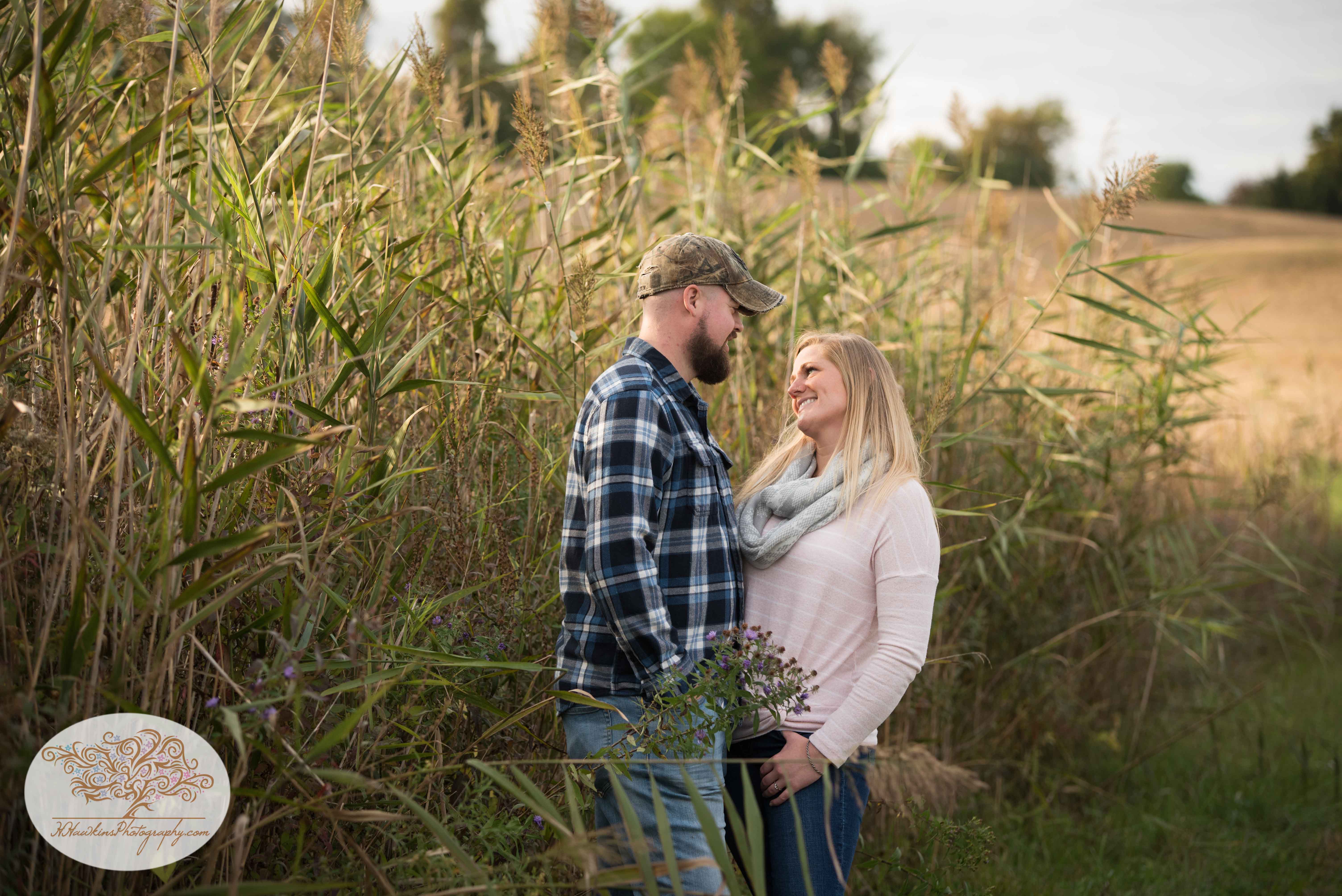 Engagement picture of bride looking at groom to be in a field