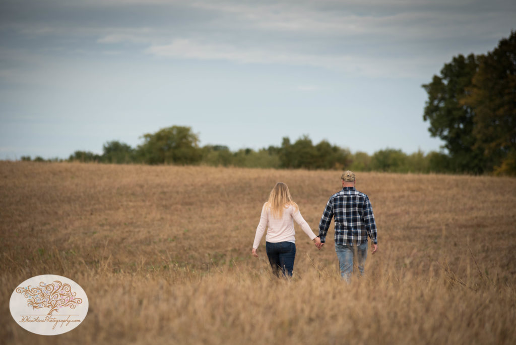 Bride and groom walk away from the camera in a field