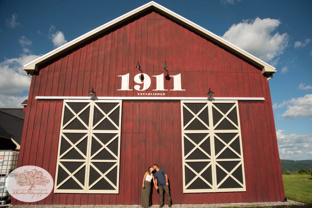 Bride and groom to be kiss in front of Beak and Skiff's 1911 Distillery barn