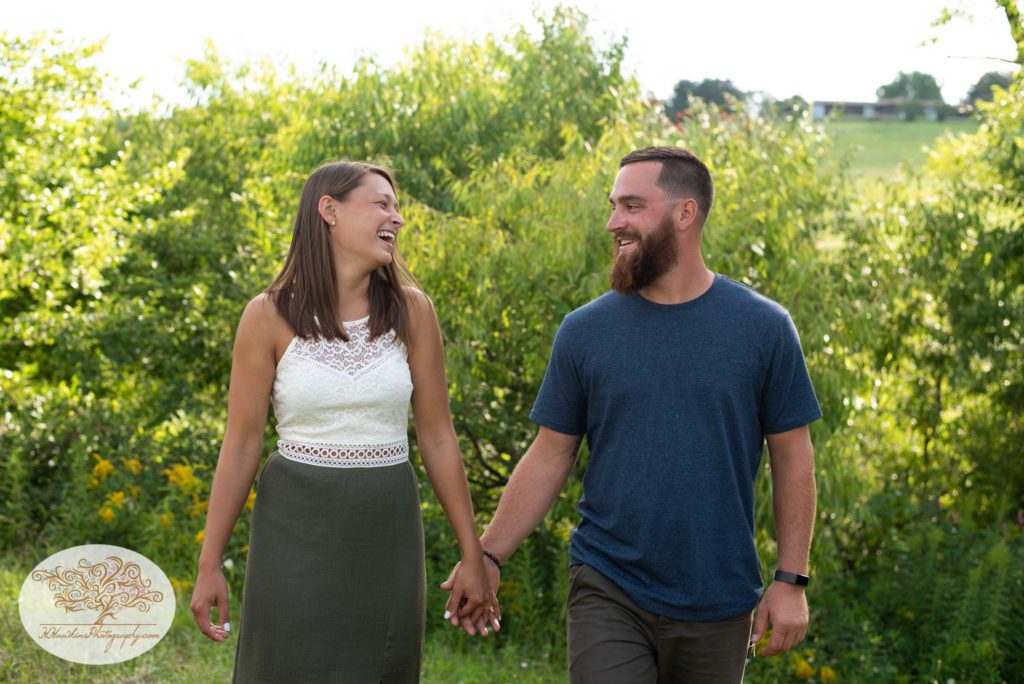 Bride and groom to be stand hand in hand at Beak and Skiff's Distillery and apple orchard