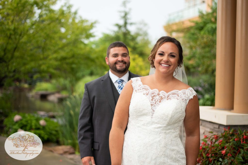 Bride and groom smile for the camera at the creek at Turning Stone Resort