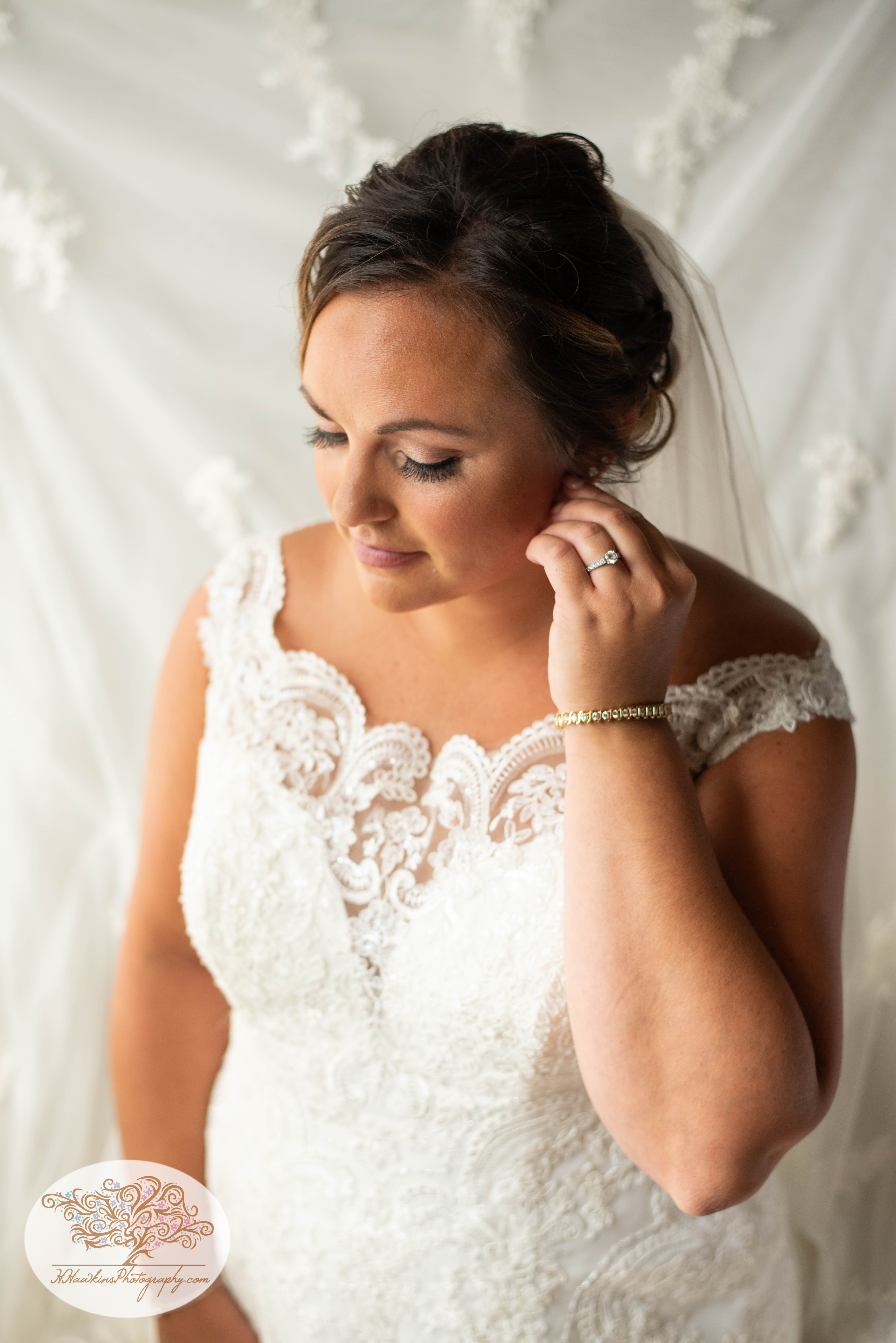 Bride adjust her earring during portrait time with Syracuse wedding photographer