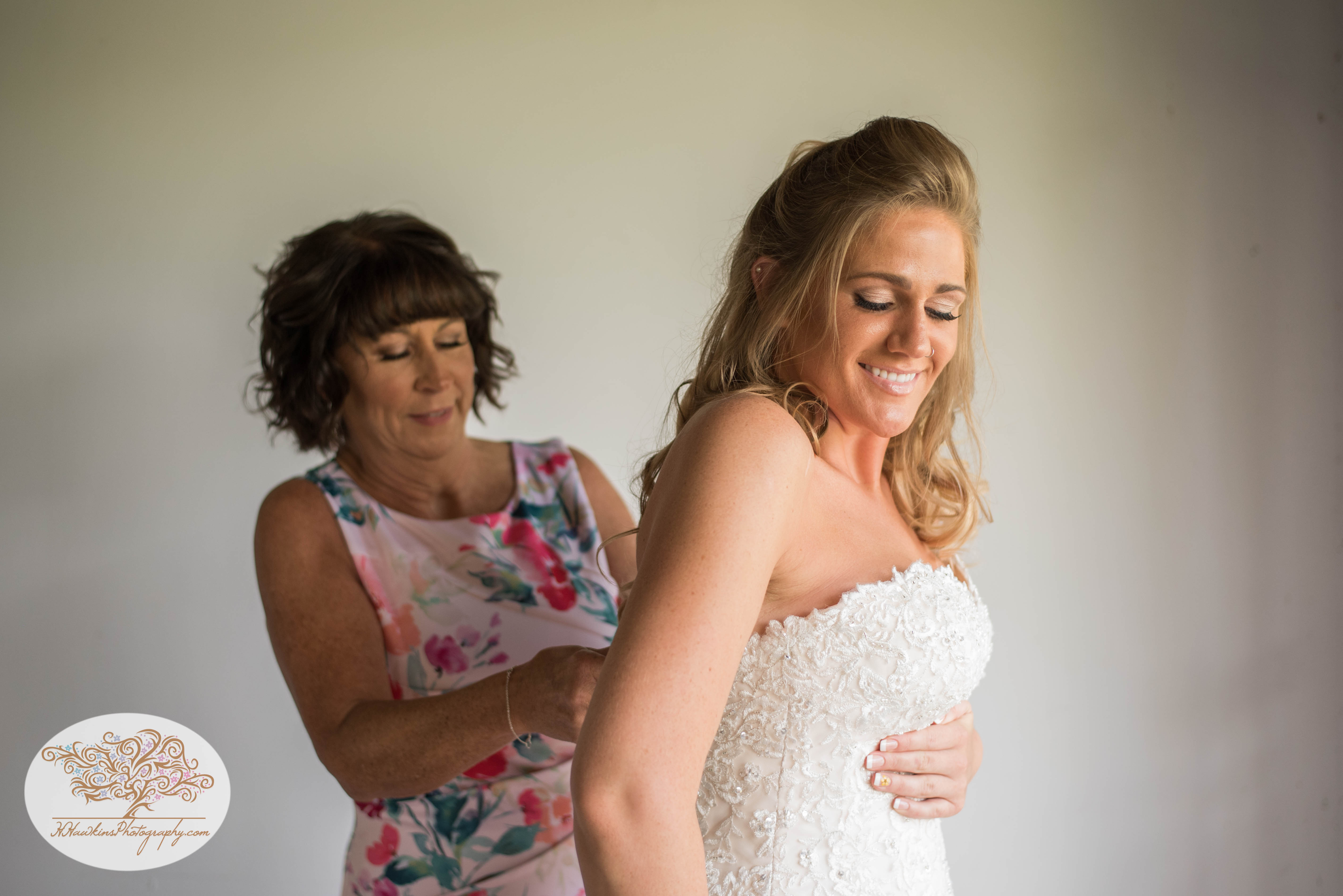 Mother helps bride by zipping up her wedding dress in Syracuse NY