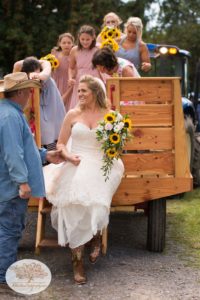 Bride gets out of hay wagon on her way to Upstate NY barn wedding