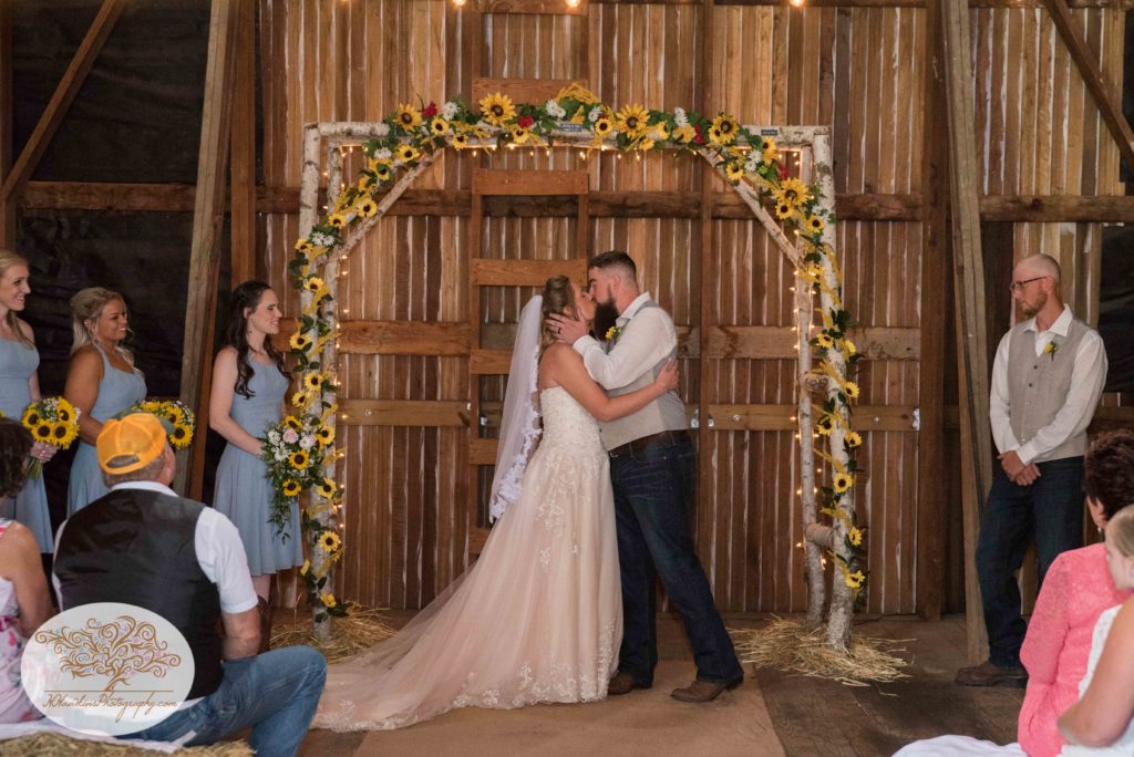 Bride and Groom kiss at the alter under their white birch arbor in their barn in Upstate NY