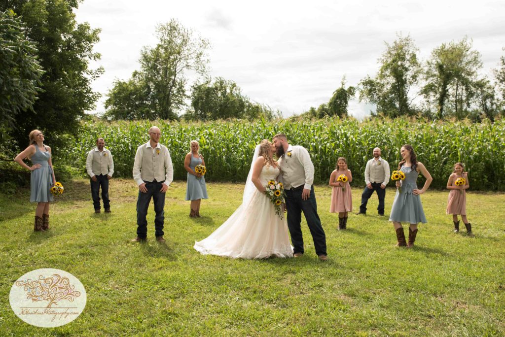 Bridal party watch as bride and groom kiss during their Upstate NY barn wedding