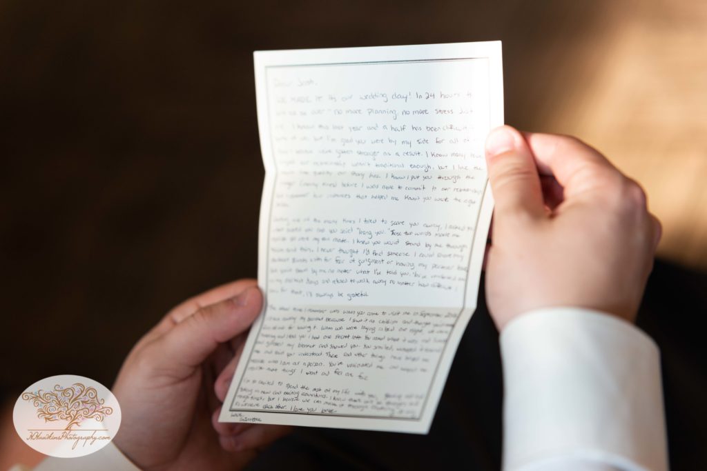 Groom holds love letter in his hands on his wedding day