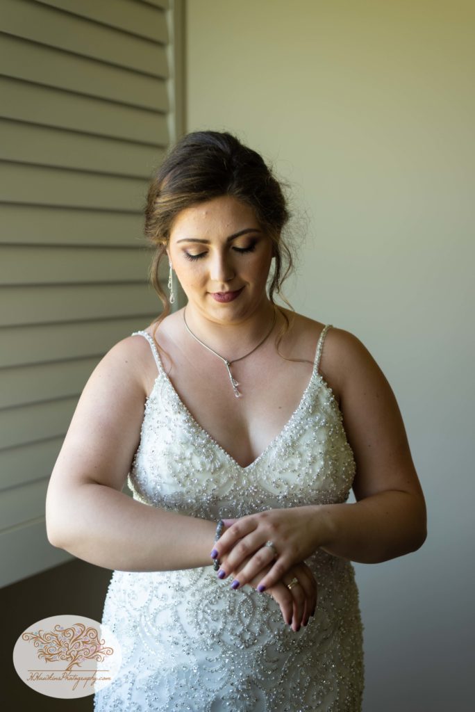 Bride in wedding dress adjusts her wedding bracelet on her wrist
