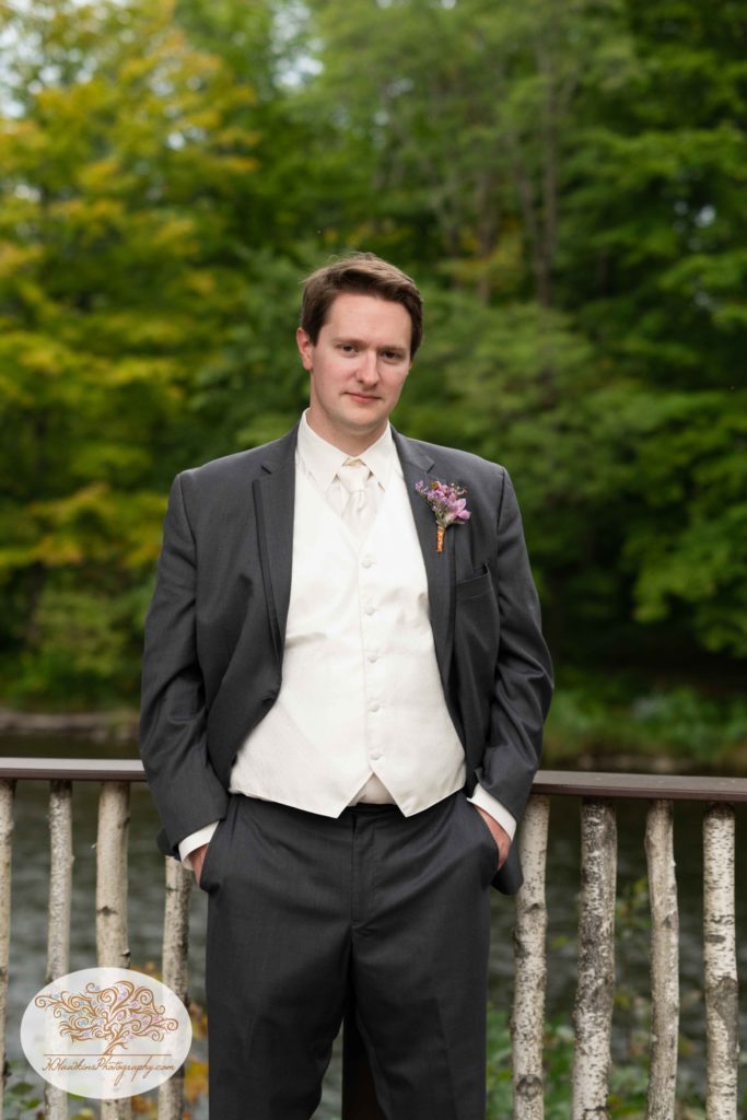 Groom on his wedding day stands with hands in pockets at Tailwater Lodge's Overlook