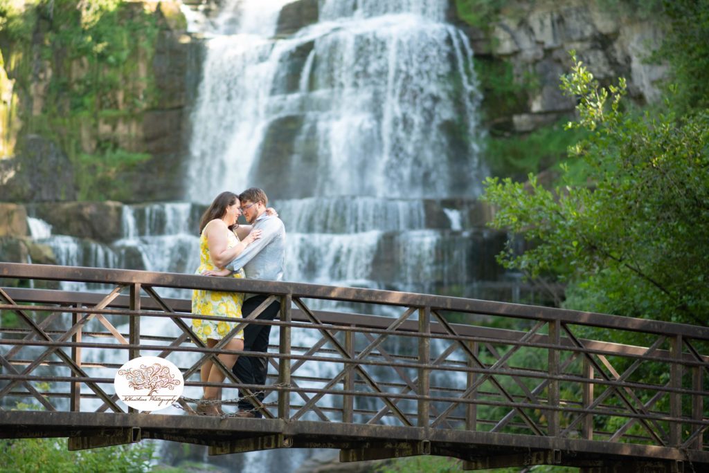 Two people in love lean forehead to forehead in front of Chittenango Falls for their engagement photos
