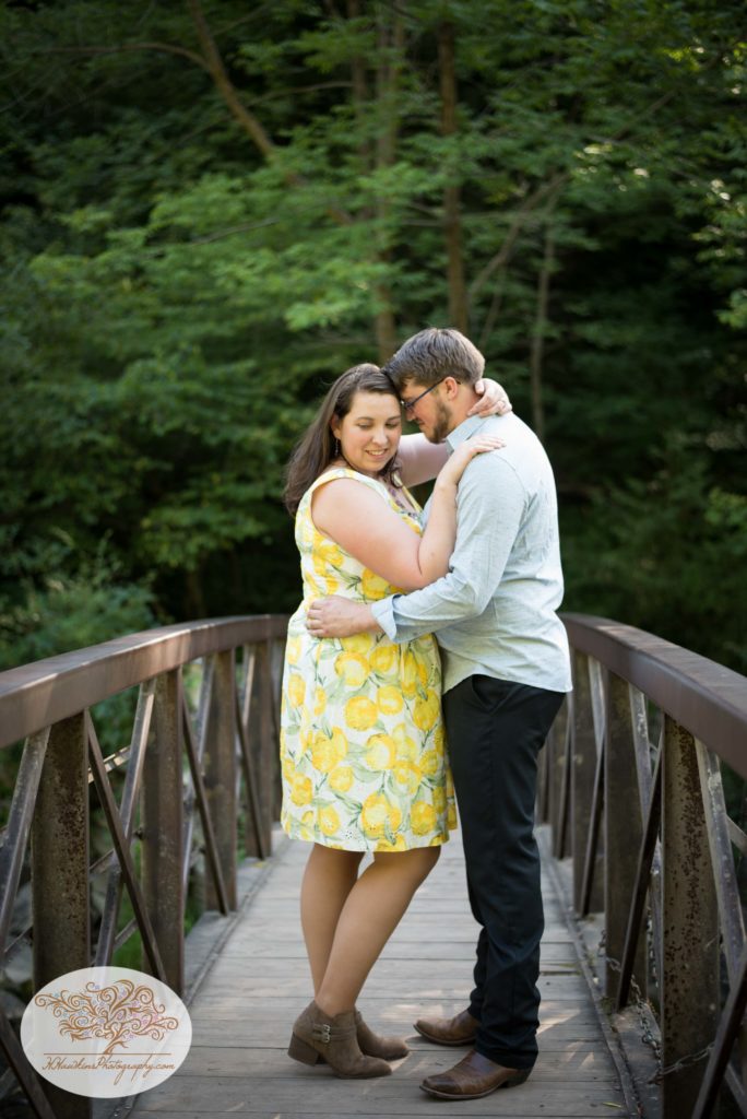 Groom nuzzles in to bride while standing on a bridge together at Chittenango Falls