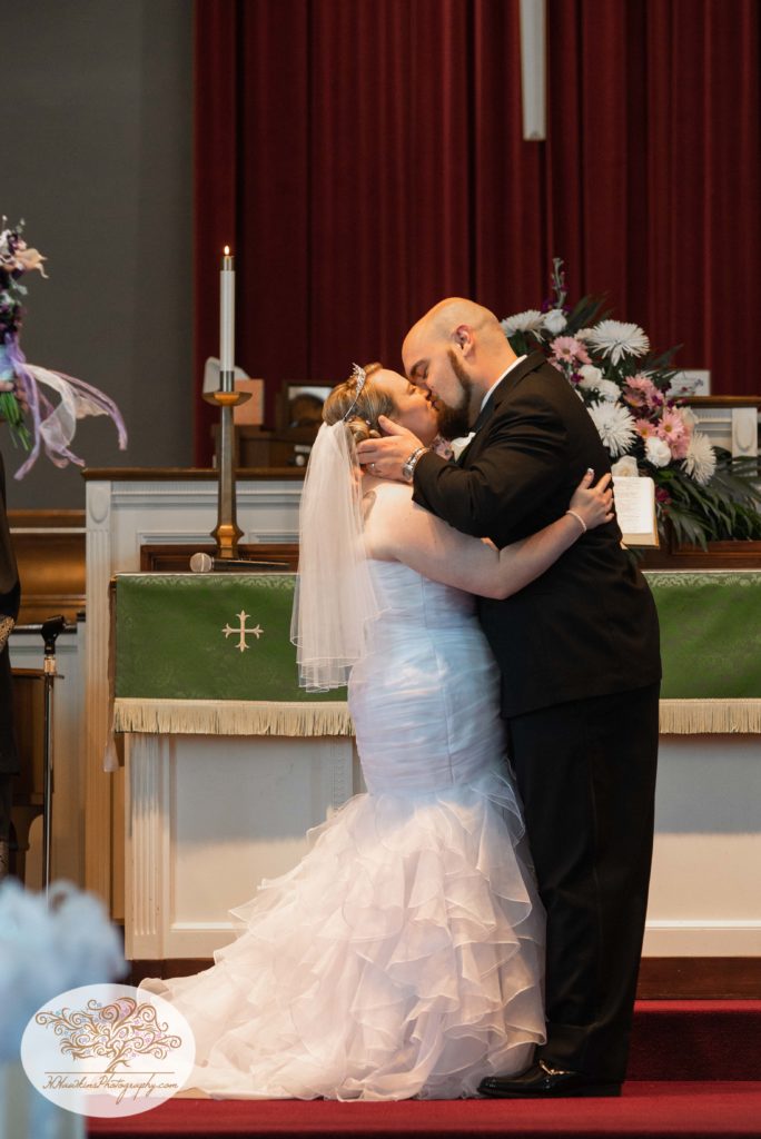 Groom and bride share their first kiss at the church altar during their wedding ceremony