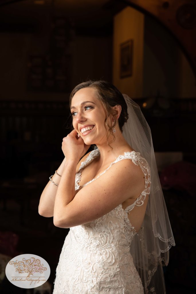 Bride smiles while putting on her earrings