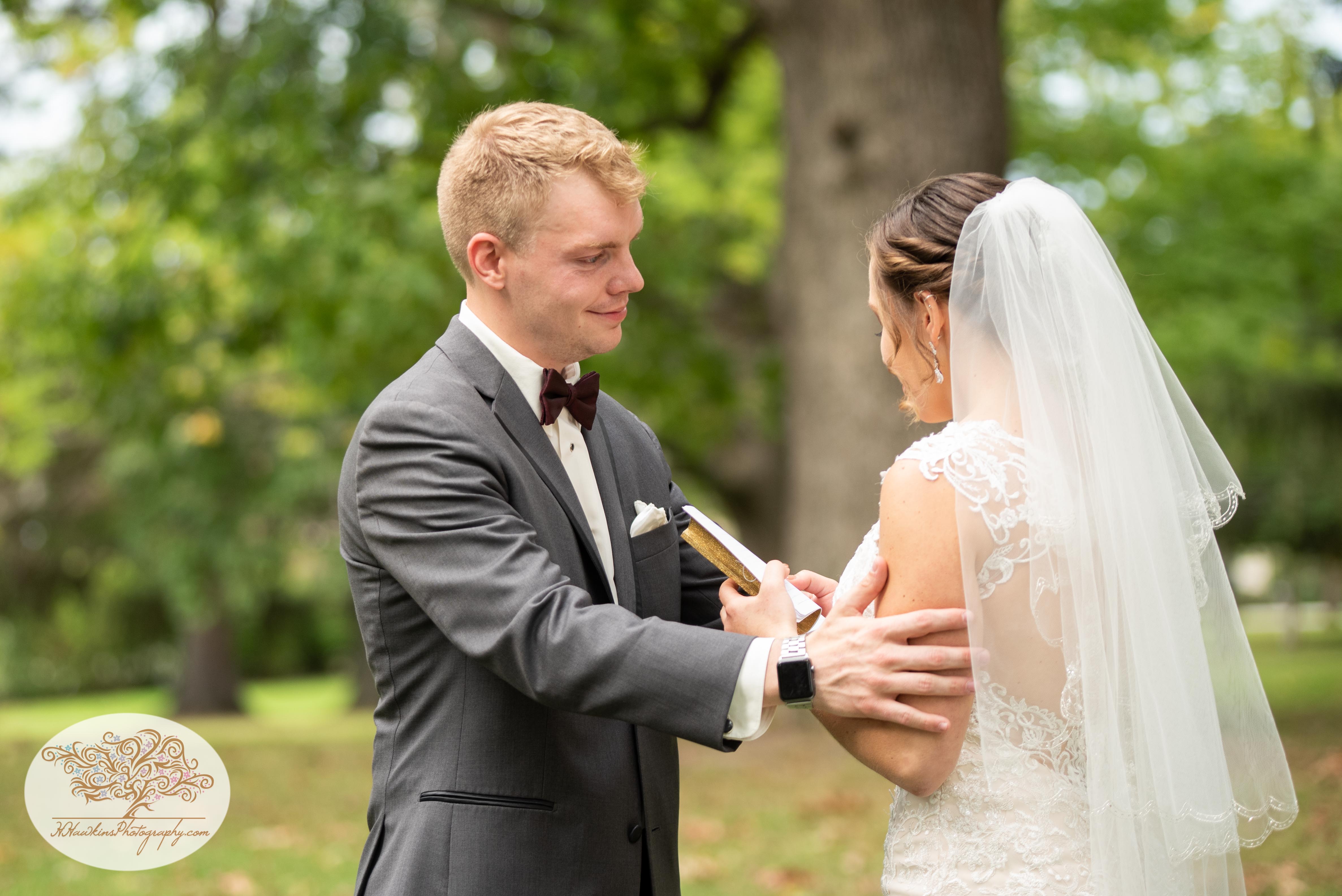 Groom comforts bride by touching her on the arm as she chokes up while reading her vows