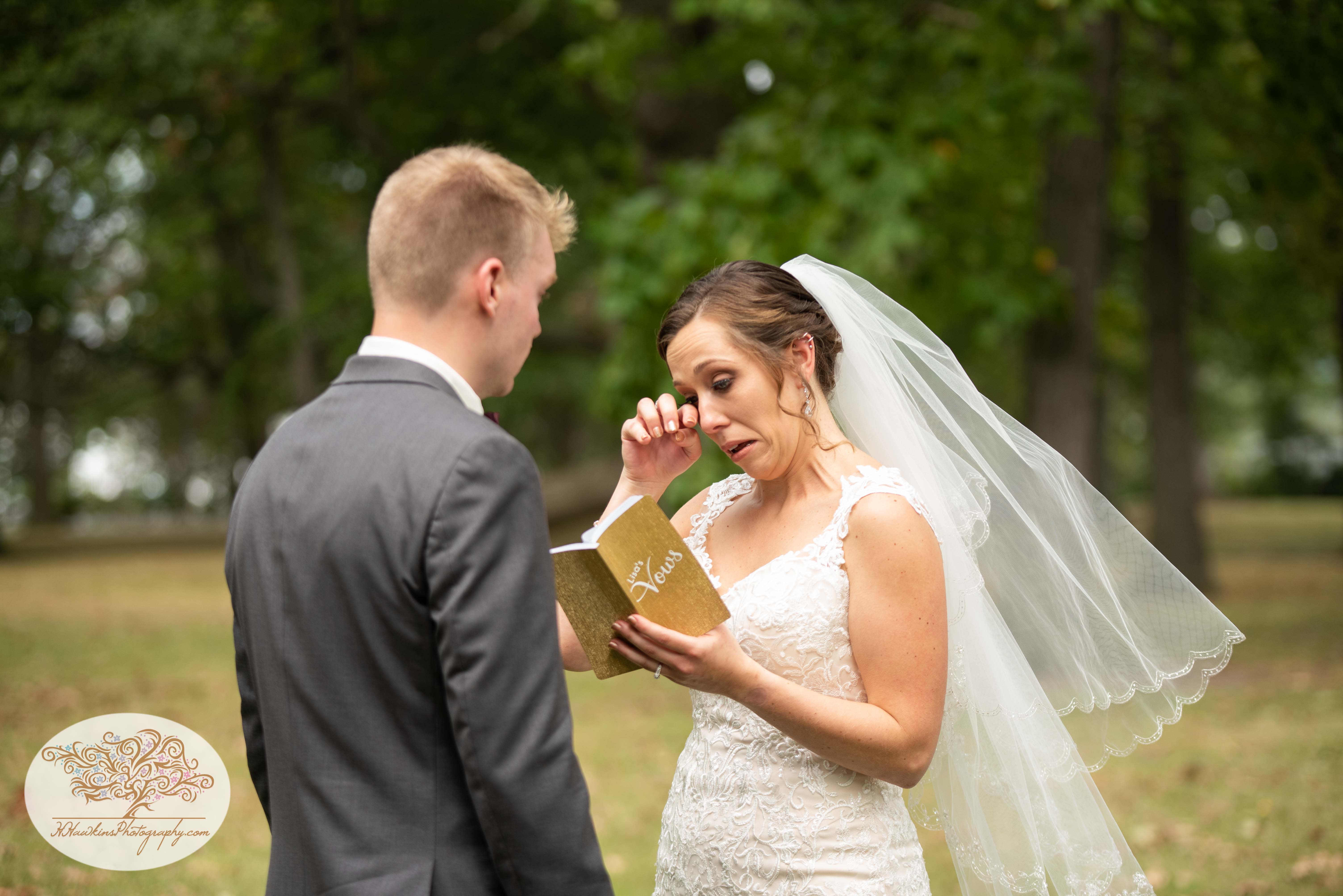 Bride wipes a tear from her eye while reading her vows to her groom