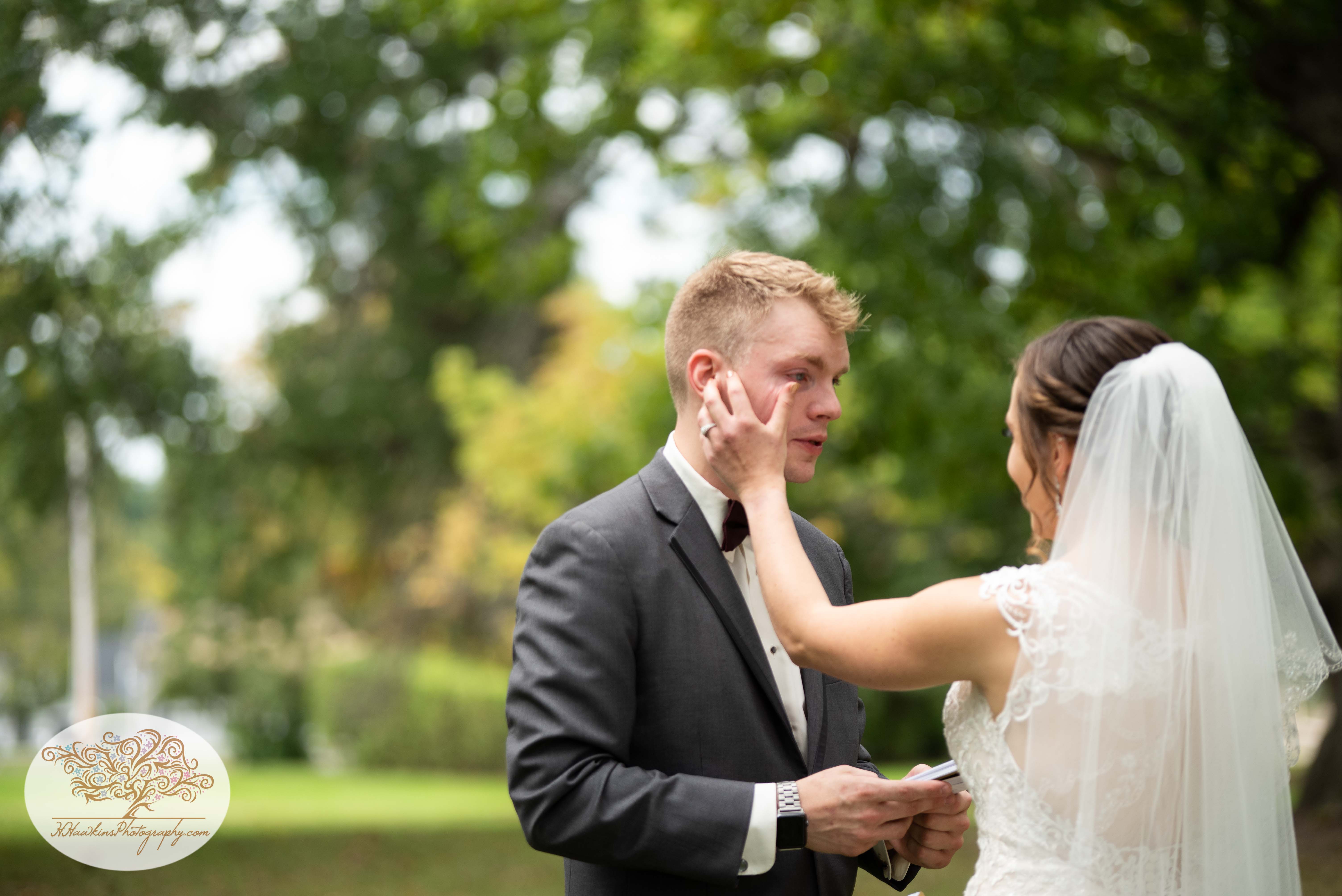 Bride wipes a tear from Groom's eyes while he reads his wedding vows to her
