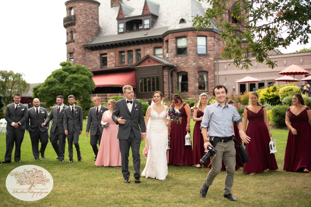 Syracuse wedding photographer walks with bridal party at upstate ny castle
