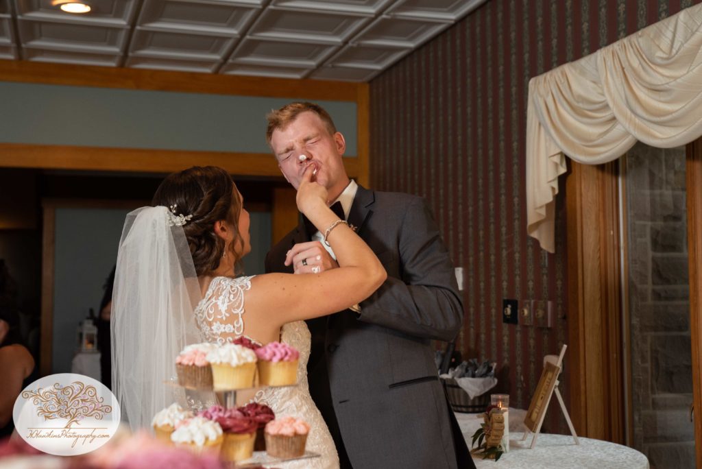 Bride gets frosting on the groom's face after their wedding cake cutting