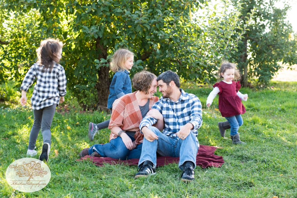 Three little girls run in circles around their mom and dad during family picture session