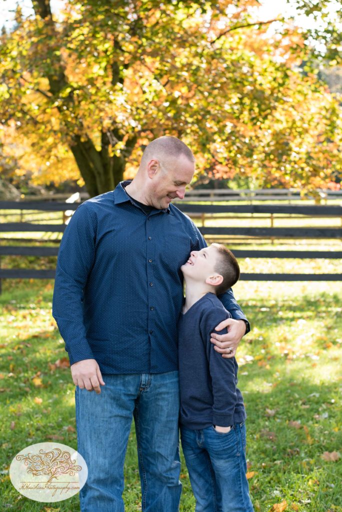 Son looks up at his dad while his dad wraps his arm around his shoulders
