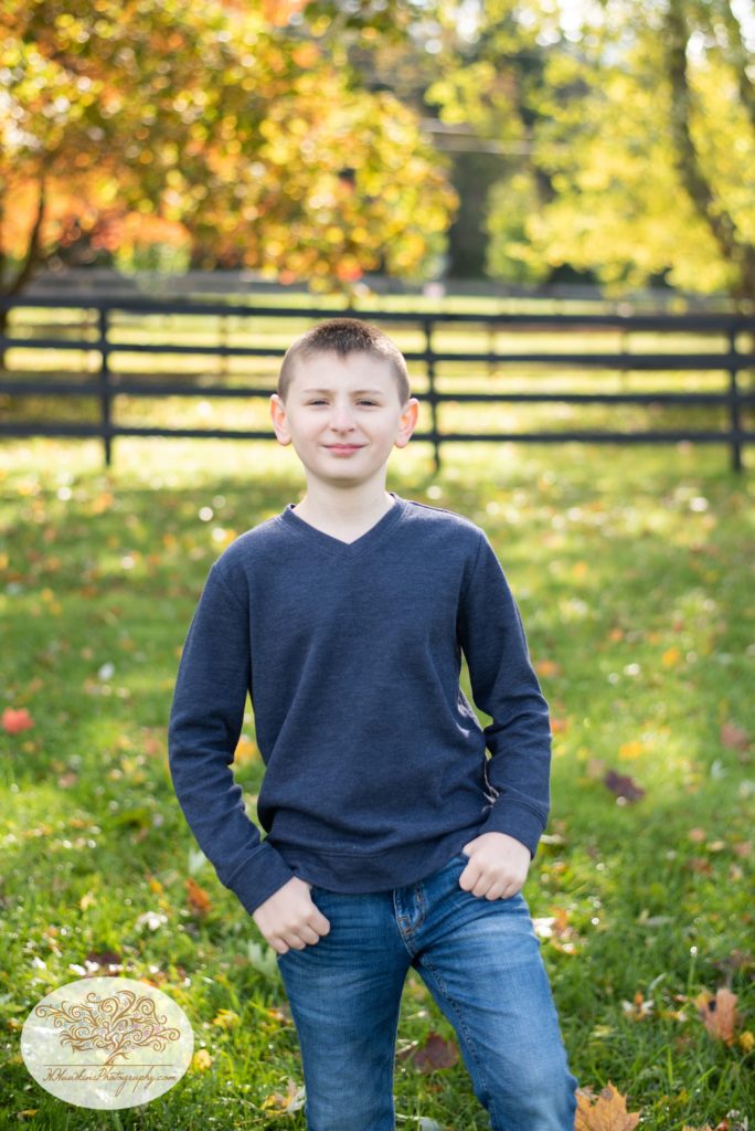 boy throws his thumbs in his pocket for a tough guy look during their picture session