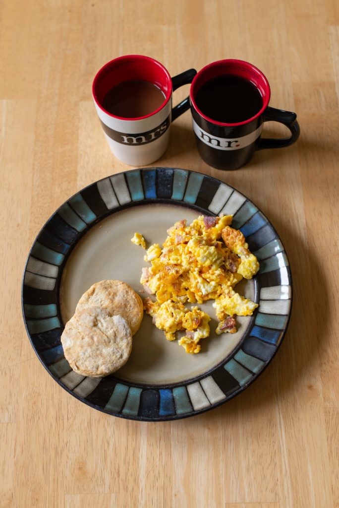 Plate with scrambled eggs, biscuits and Mr. & Mrs. coffee mugs