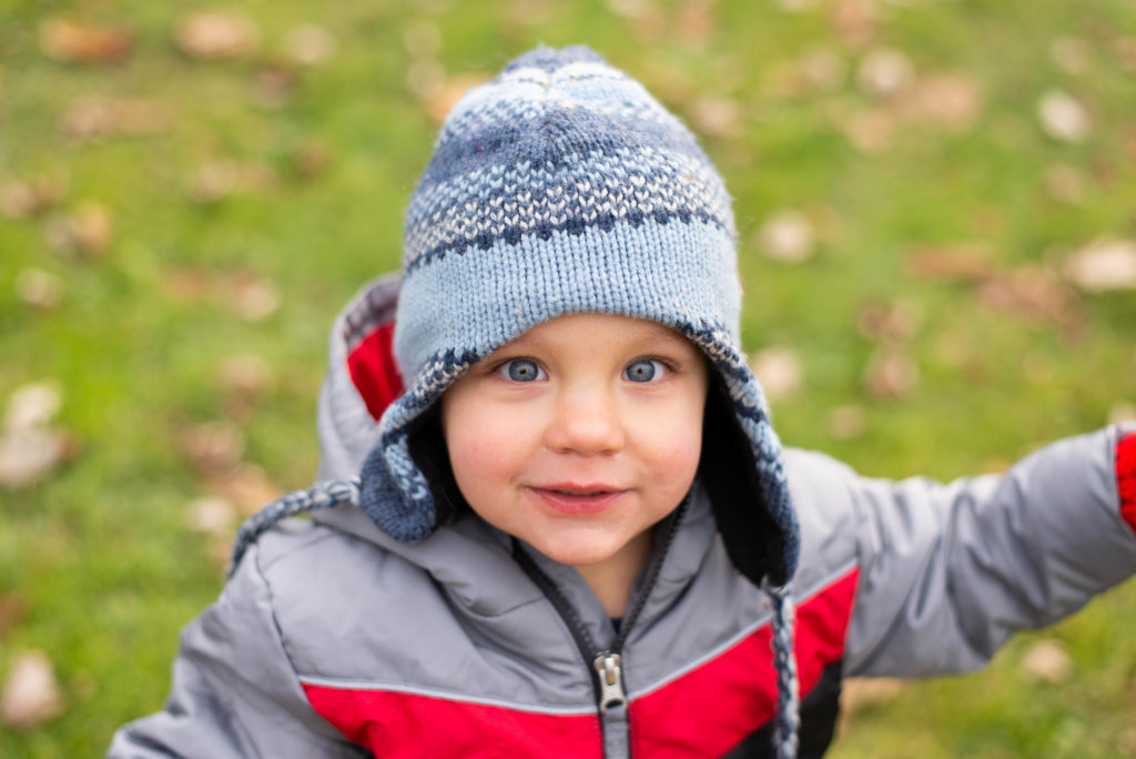 Little boy in blue winter hat looks up at camera