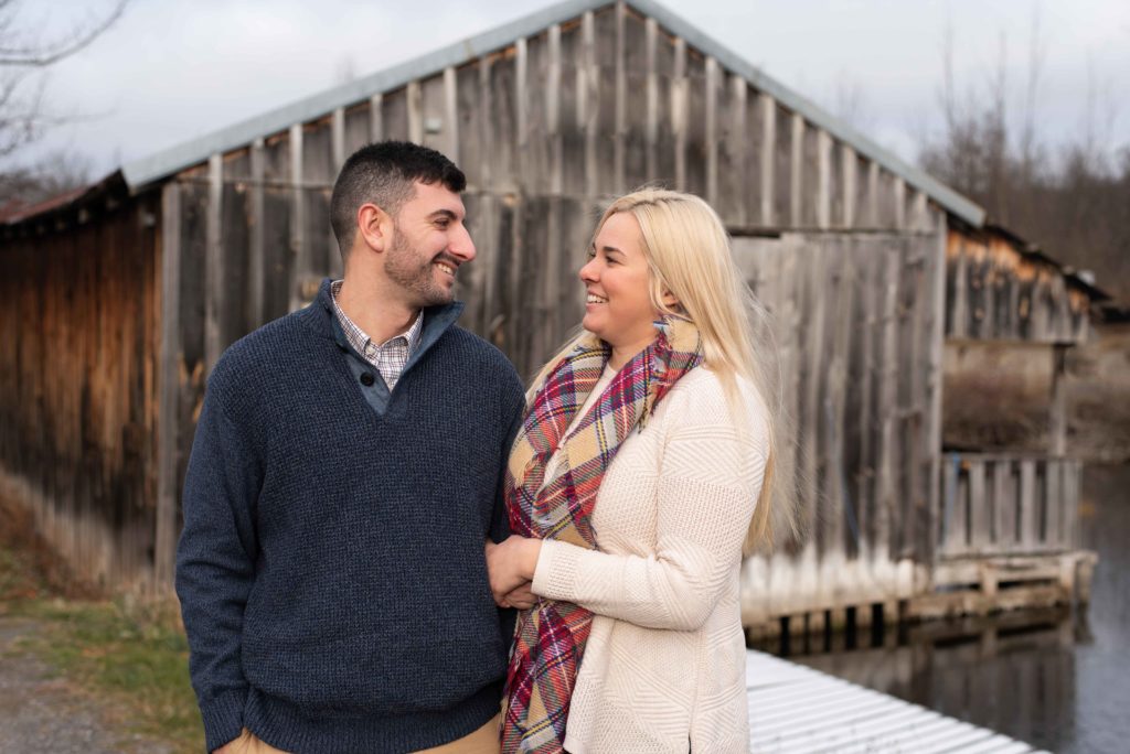 Engaged couple stands together looking at each other during their fall engagement photo session in Syracuse NY