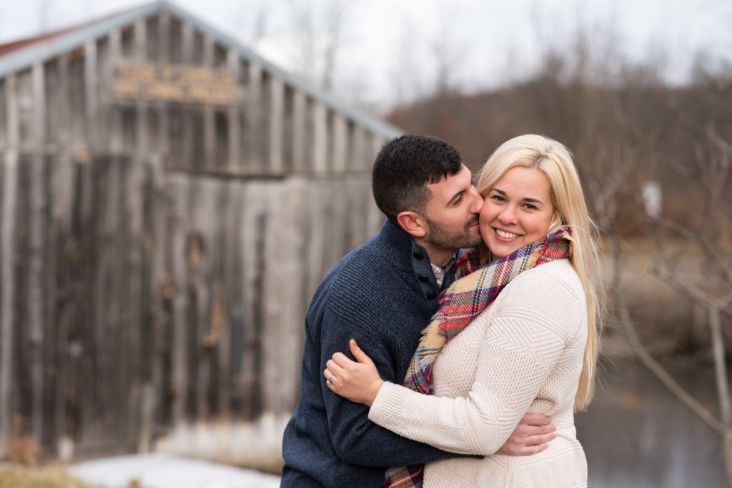 Groom to be kisses his bride on the cheek while standing beside Erie Canal