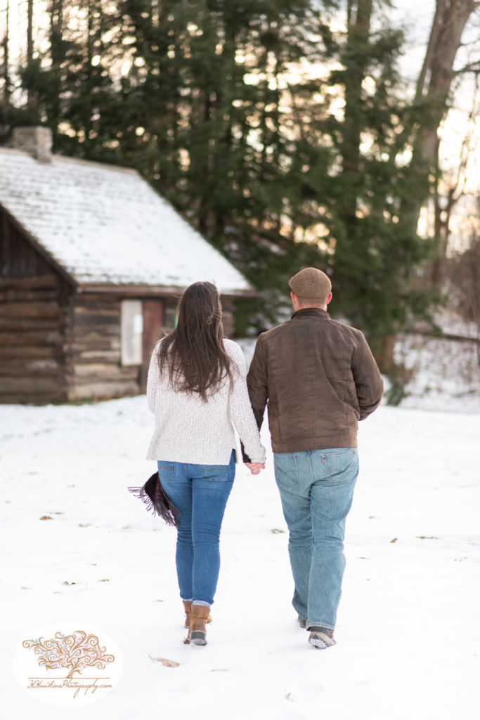 Engaged couple walks towards Fillmore Glen replica log cabin