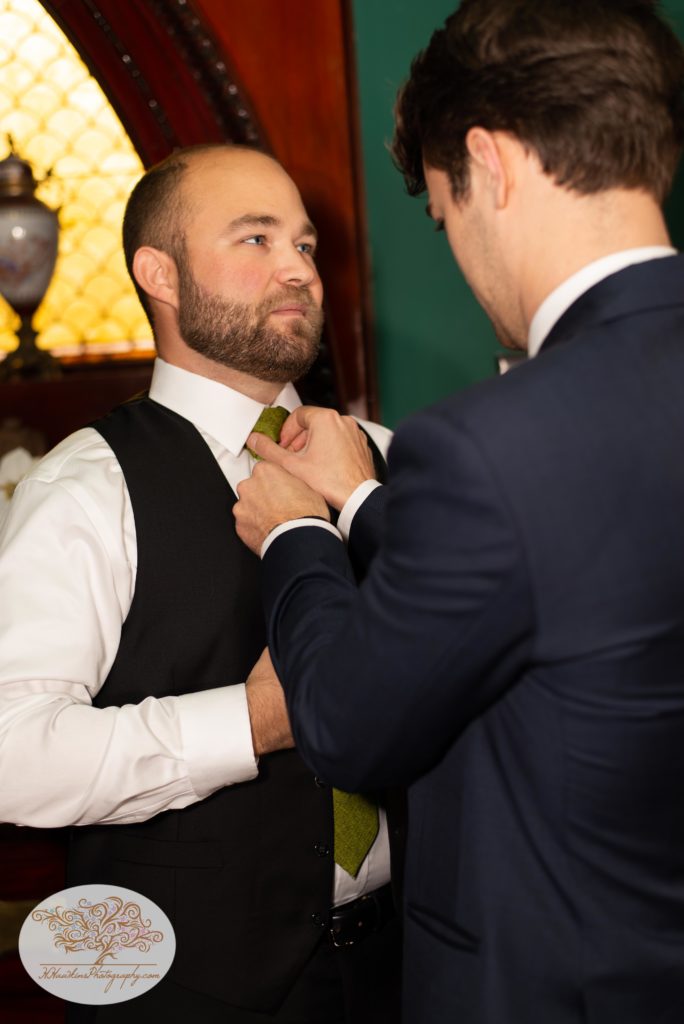 Groom adjusts his tie as he gets ready for his wedding day