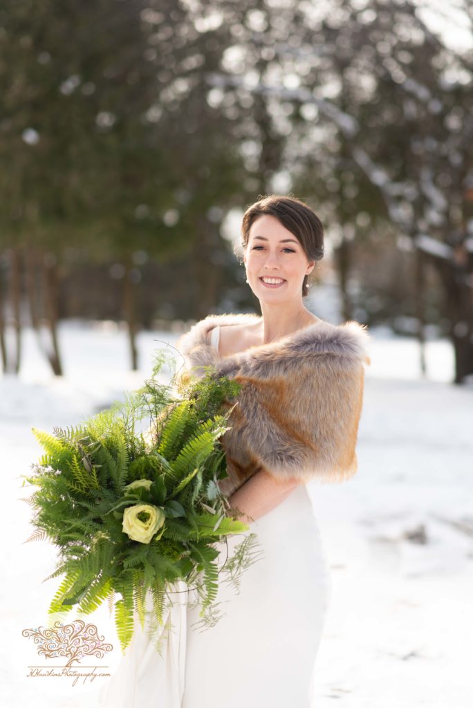 Portrait of bride standing in the snow with her green wedding bouquet