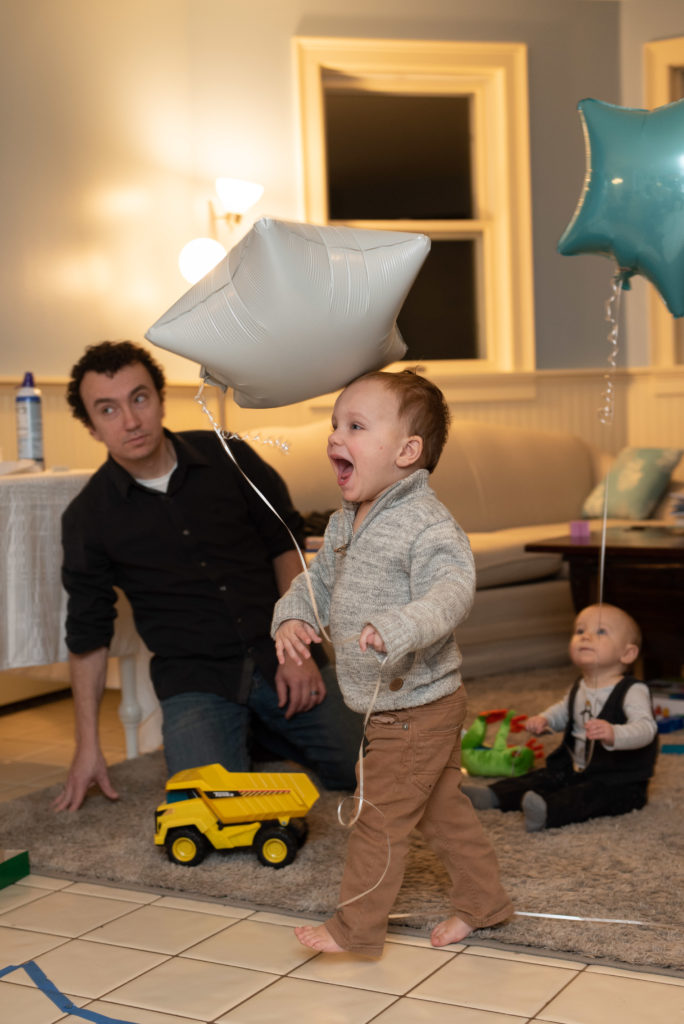 dad and sons play with birthday balloons for penguin themed party
