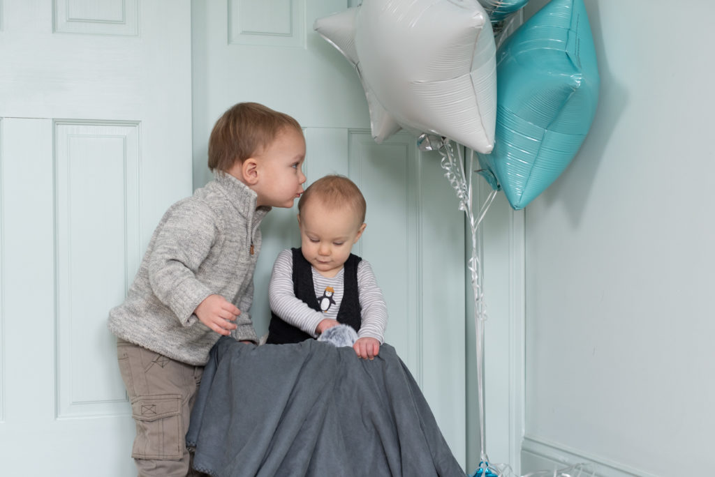 big brother kisses little brother on the head during one year old portrait session