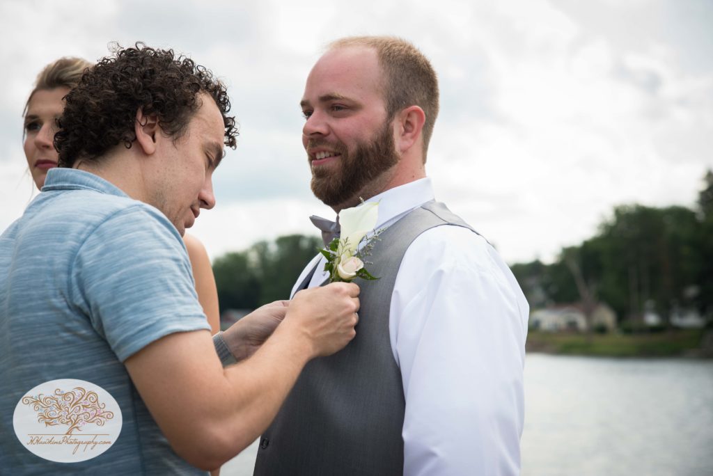 Photographer pins boutonnière for groom
