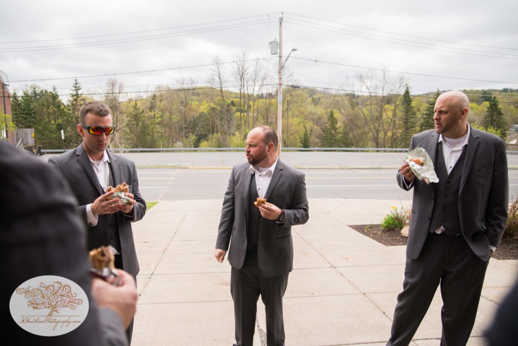 Groomsmen stand around before the ceremony eating Arby's for lunch