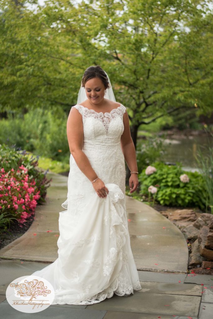 Bride swishes her wedding dress back and forth while walking through garden at Turning Stone