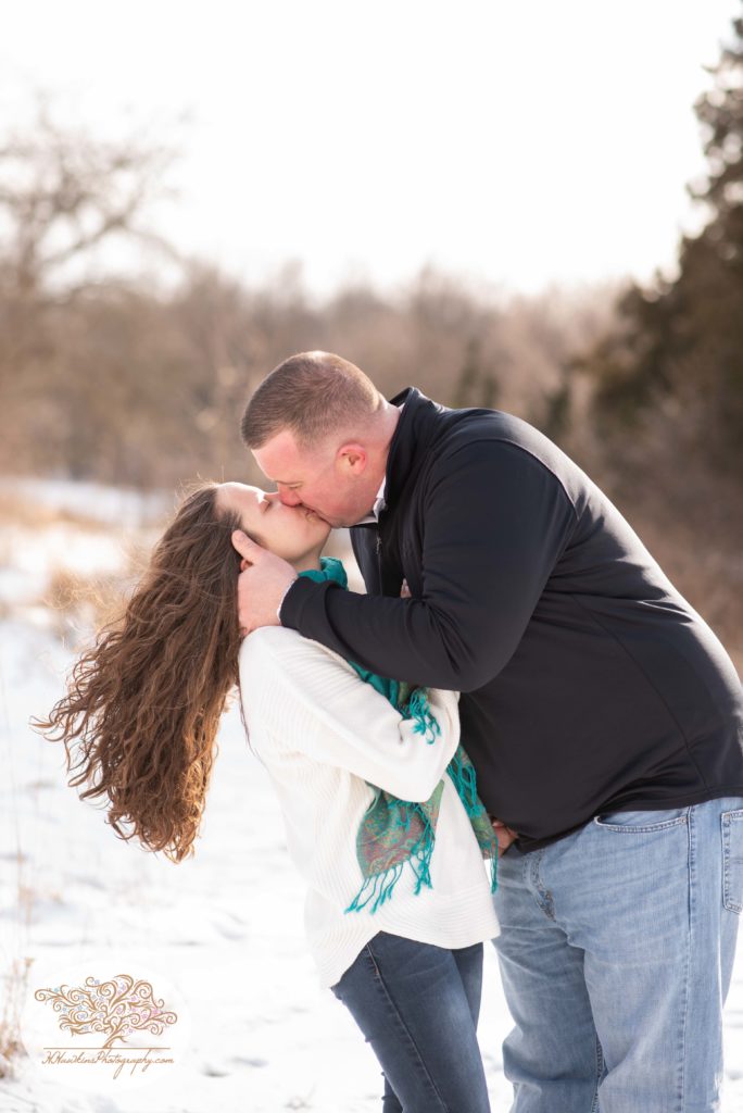 bride and groom kiss as her hair flows out in the wind behind her in a snowy field in upstate ny