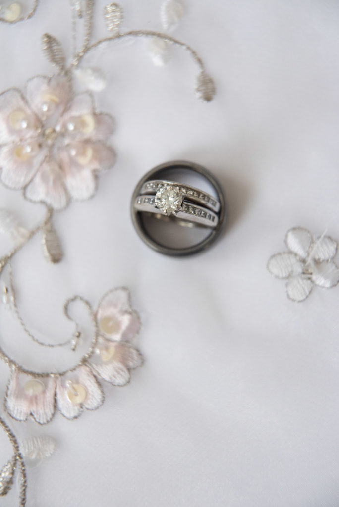 diamond ring and wedding bands with wedding dress as background with small flowers