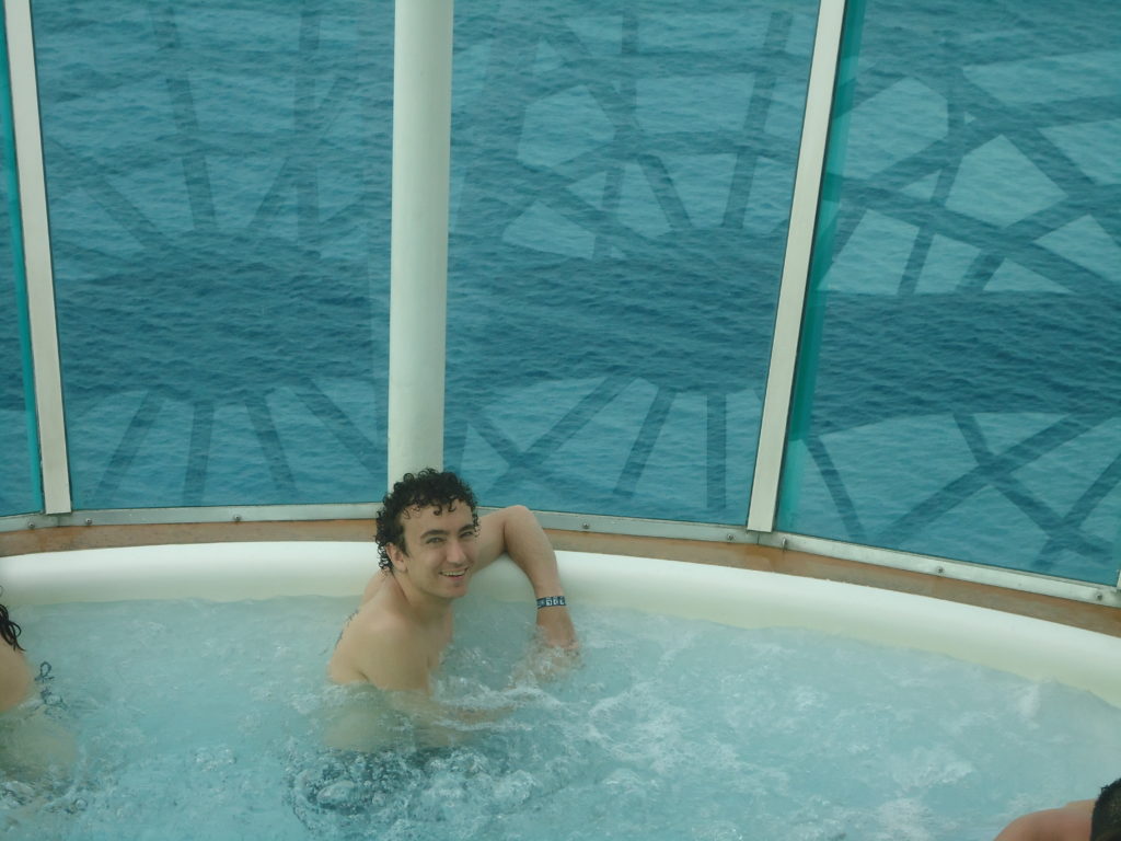 man sits in Freedom of the Seas's hot tub overlooking the ocean