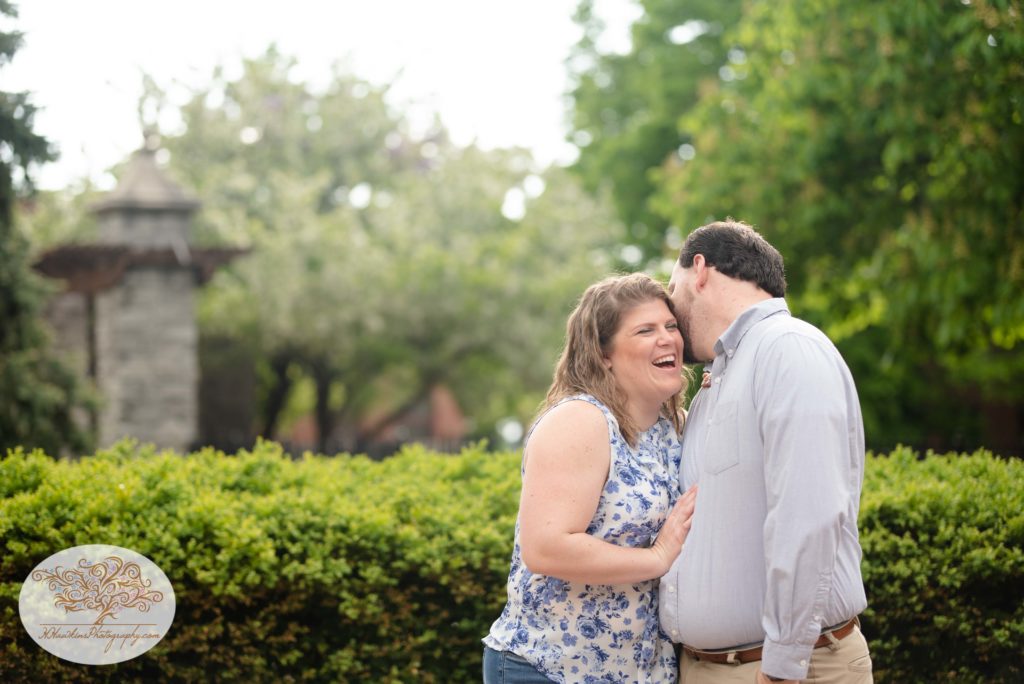 Bride laughs as groom whispers in her ear by Syracuse engagement photographer