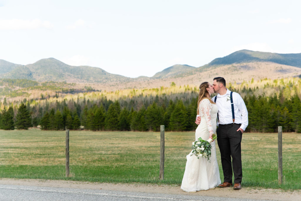 Bride and groom kiss in front of The Sentinel Mountains in Lake Placid NY by Adirondack Wedding Photographer