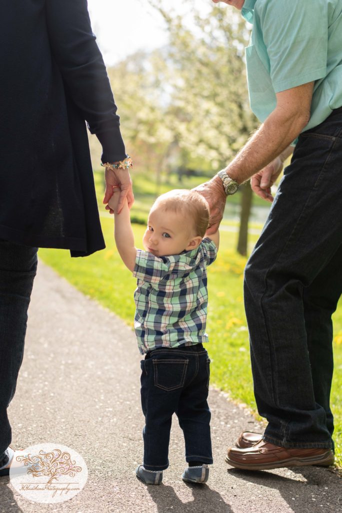 Baby grandson walks between grandparents holding their hands