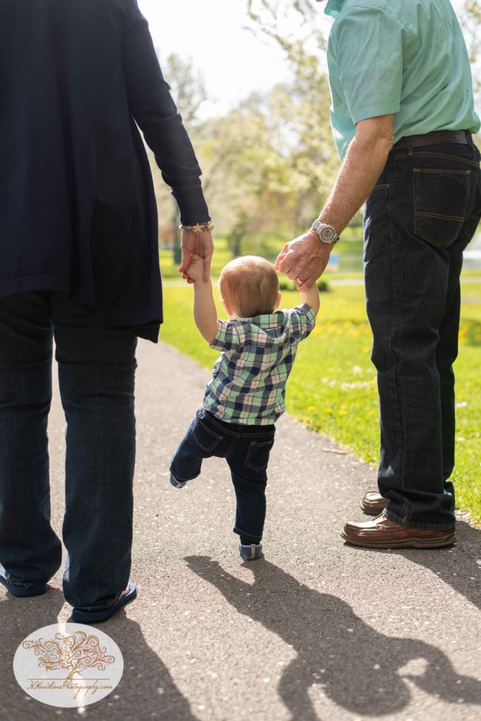 Baby grandson walks between grandparents holding their hands