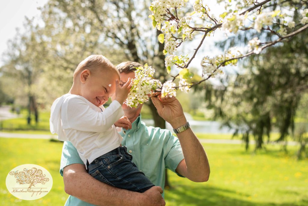 Grandpa teases grandson with a blossom from a tree branch