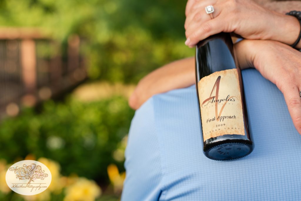 Bride to be holds bottle of wine from Anyela's Vineyard with her engagement diamond ring showing