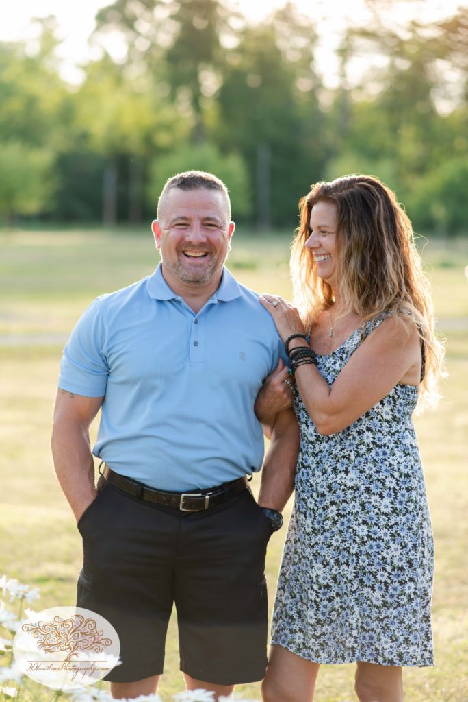 Bride and groom stand in a field with the sun behind their backs at Anyela's Vineyard in Skaneateles NY